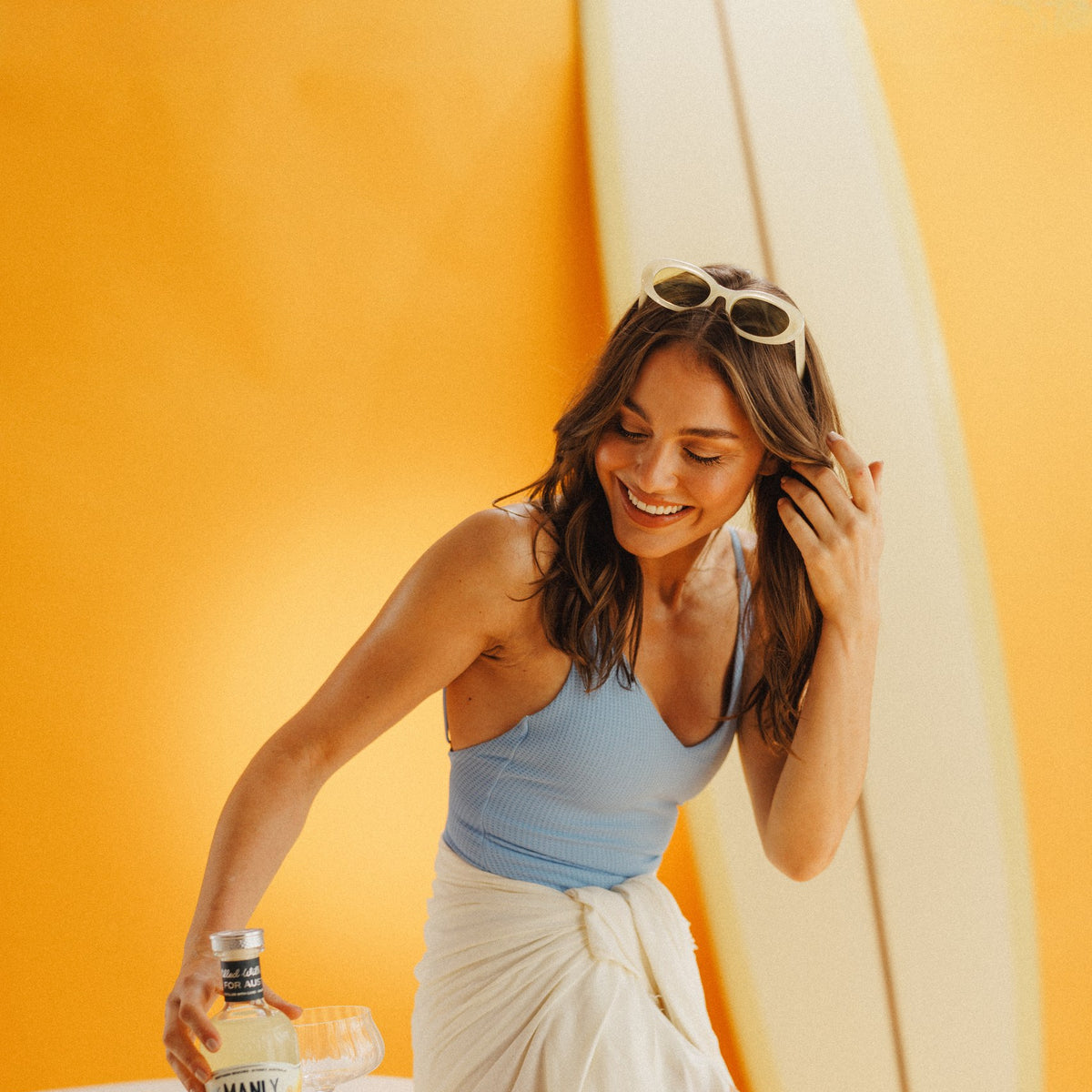 Reaching for a bottle of Limontivo beside a bowl of lemons, surfboard behind
