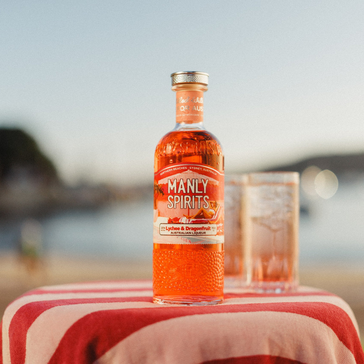 Lychee & Dragonfruit Liqueur with two Lychee & Dragonfruit Spritzes by the water
