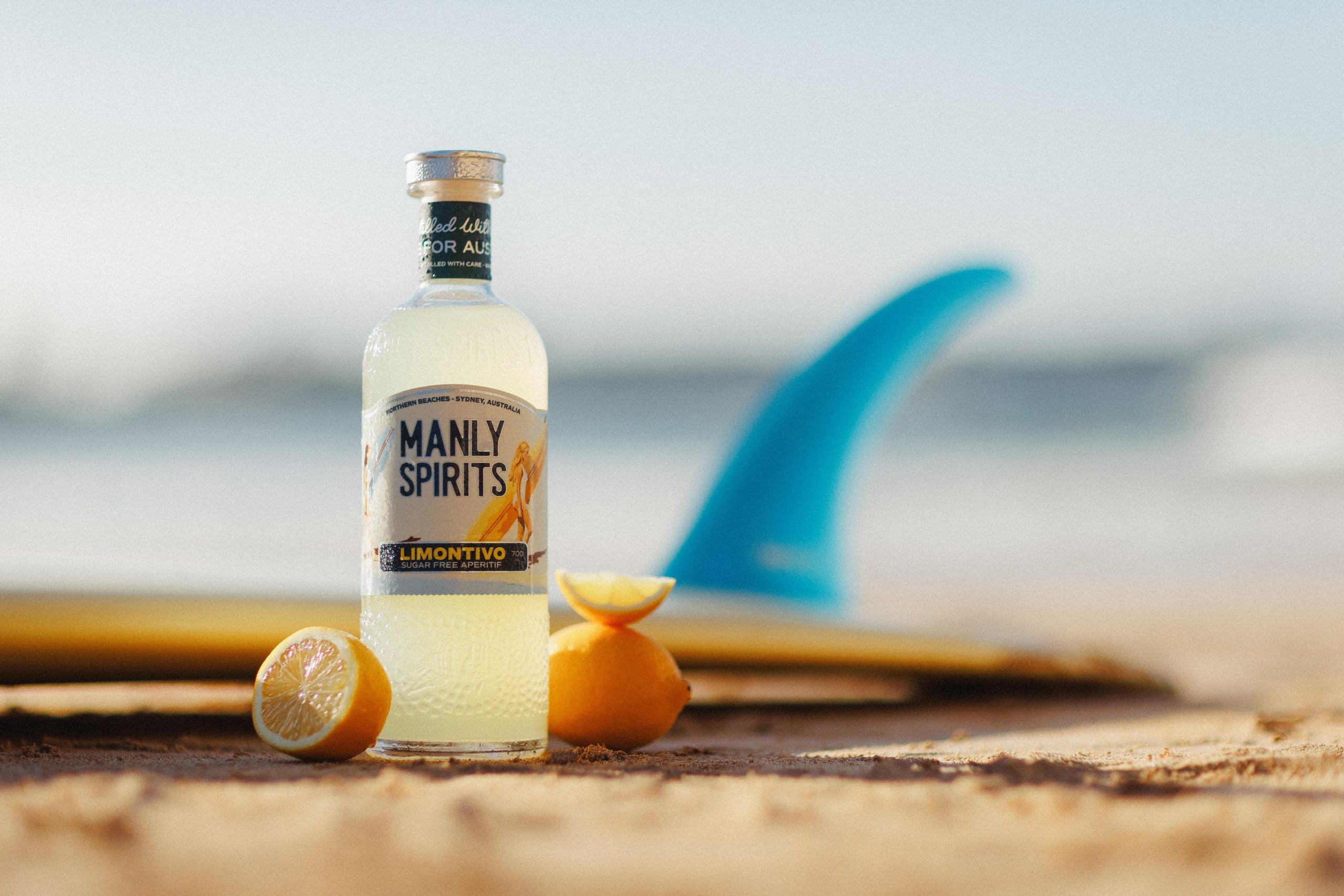 Limontivo with halved lemons on the sand beside a surfboard