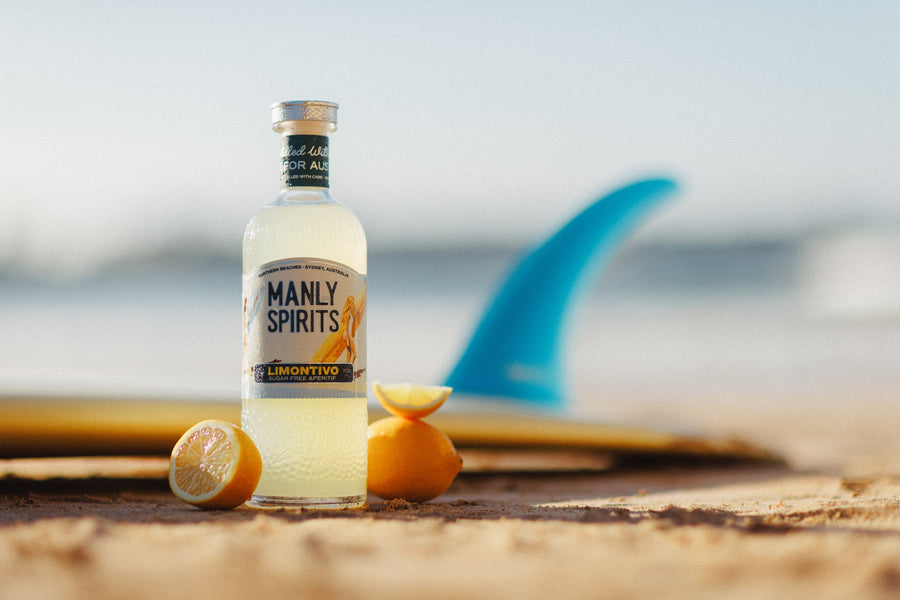 Limontivo with halved lemons on the sand beside a surfboard