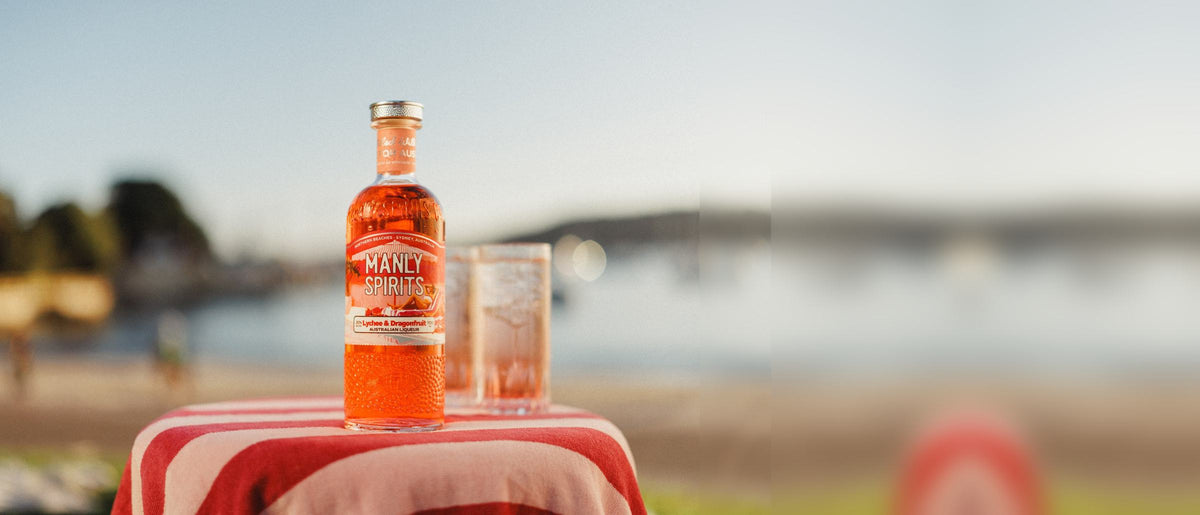 Lychee & Dragonfruit Liqueur and a Paradise Spritz on a striped towel by the harbour